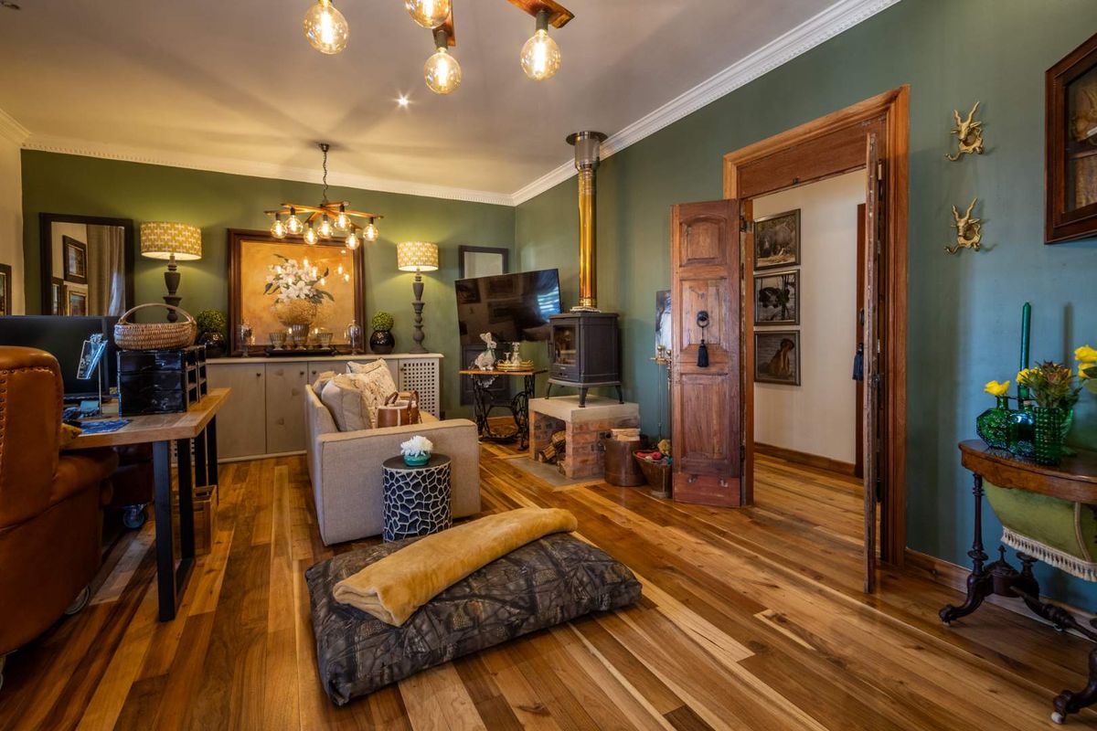 A cozy living room featuring rich hardwood flooring, a wood-burning stove, and elegant crown molding, creating a warm and inviting atmosphere.