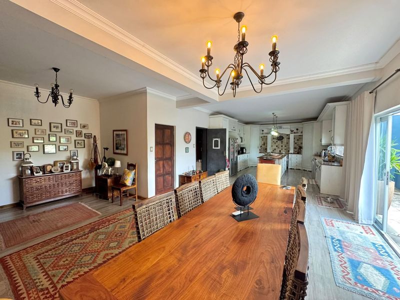 Spacious open-plan living and dining area featuring a large wooden dining table, chandelier lighting, and a seamless transition to a well-appointed kitchen.
