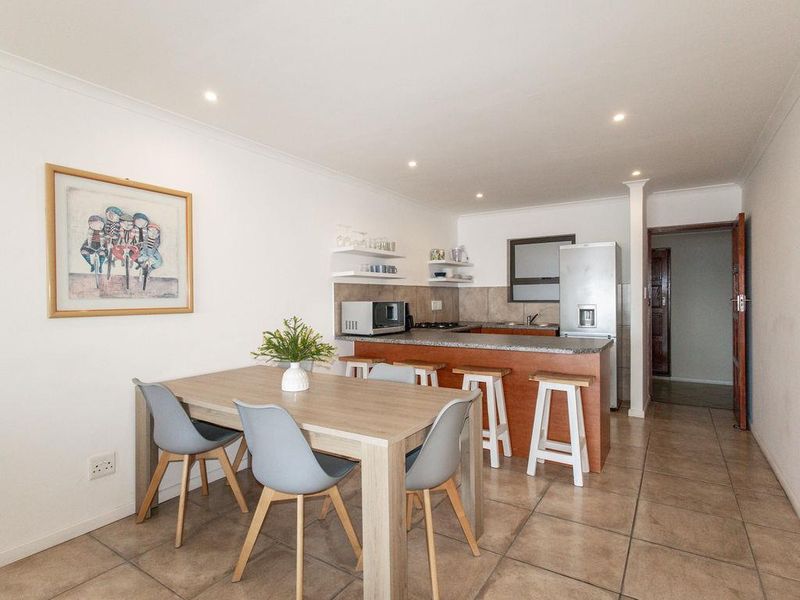 Open-plan kitchen and dining area featuring tiled flooring, granite countertops, and a breakfast bar, providing a functional and connected living space.