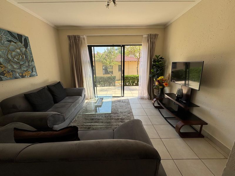 A comfortable living room featuring tiled flooring and a large sliding glass door that provides natural light and access to the outdoor area.