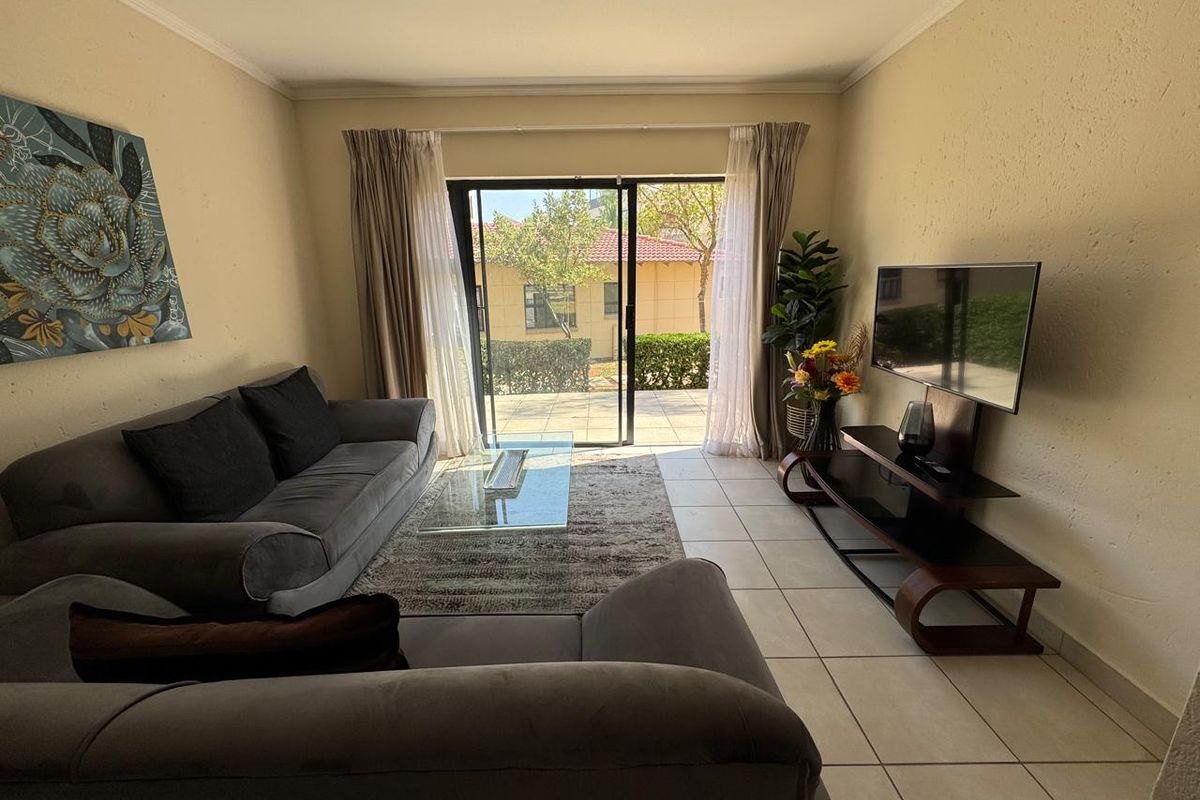 A comfortable living room featuring tiled flooring and a large sliding glass door that provides natural light and access to the outdoor area.