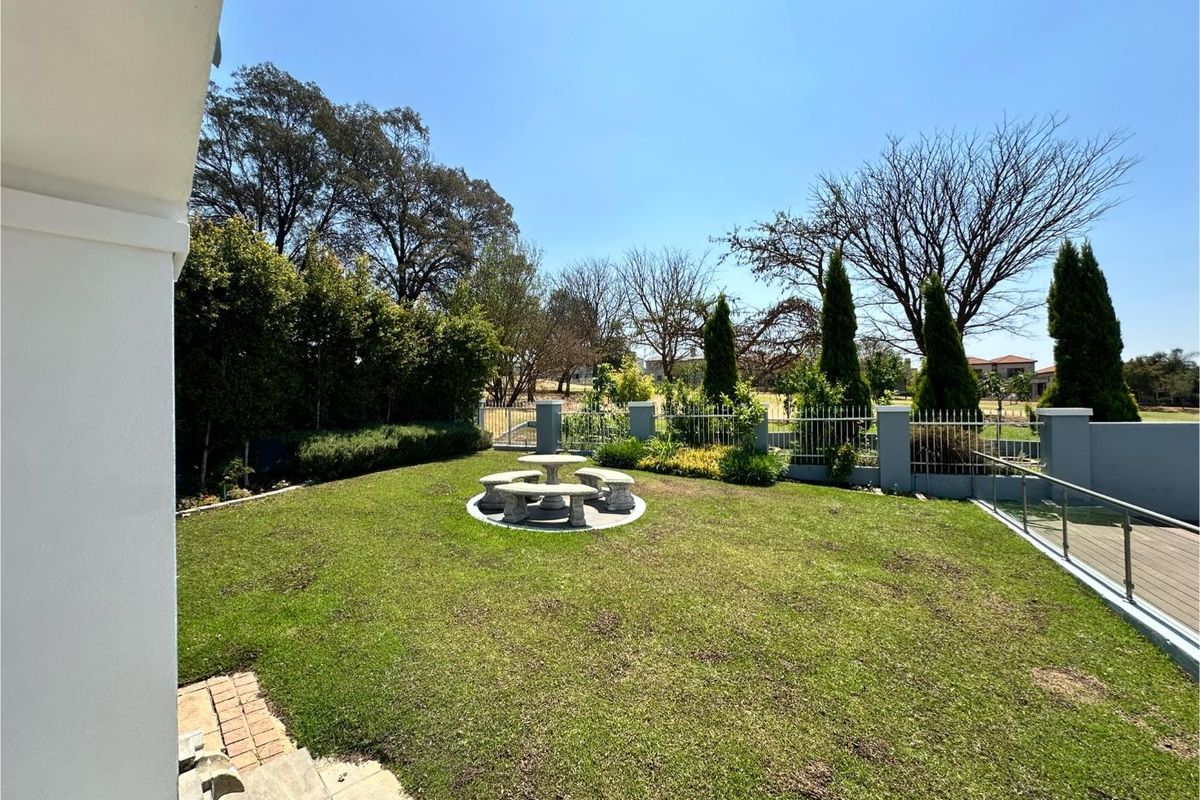 A well-maintained rear garden featuring a manicured lawn, perimeter fencing, and established landscaping, providing a private outdoor space.