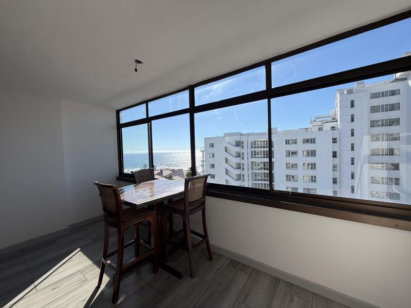 Enclosed balcony area featuring large windows with ocean and city views, finished with modern tiled flooring.