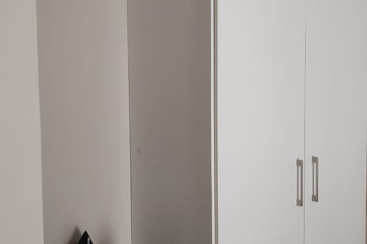 A bedroom featuring a built-in white wardrobe with modern handles, providing functional storage space.