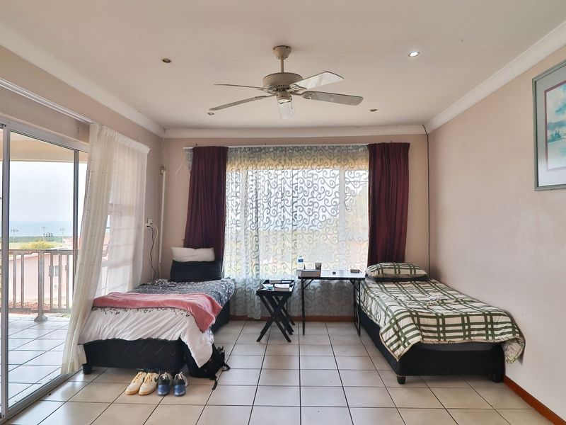 Spacious bedroom featuring tiled flooring, a ceiling fan, and large sliding glass doors that provide access to an outdoor balcony area.