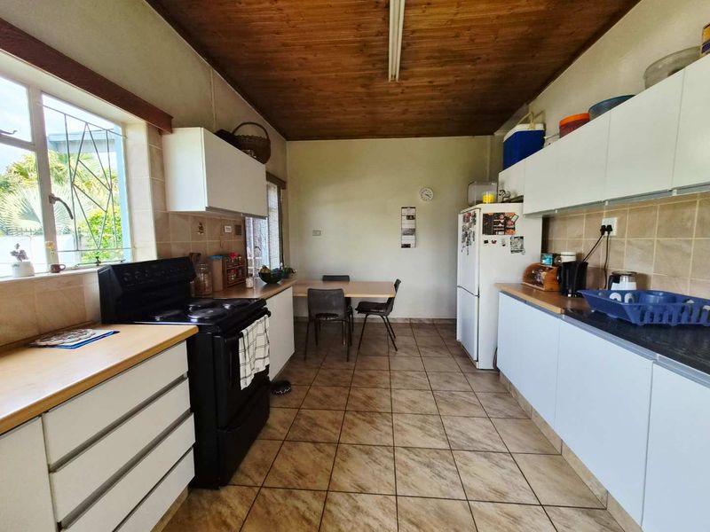 A functional kitchen featuring tiled flooring, wooden ceiling, ample built-in cabinetry, and a tiled backsplash, offering a practical layout for daily meal preparation.