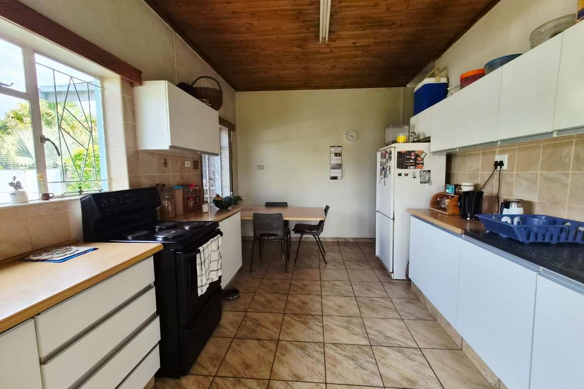 A functional kitchen featuring tiled flooring, wooden ceiling, ample built-in cabinetry, and a tiled backsplash, offering a practical layout for daily meal preparation.