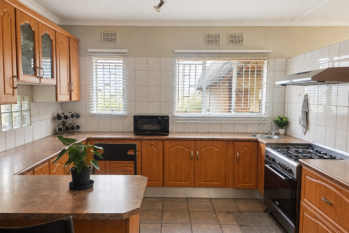 A functional kitchen featuring wooden cabinetry, laminate countertops, a gas stove with extractor fan, and tiled finishes throughout.