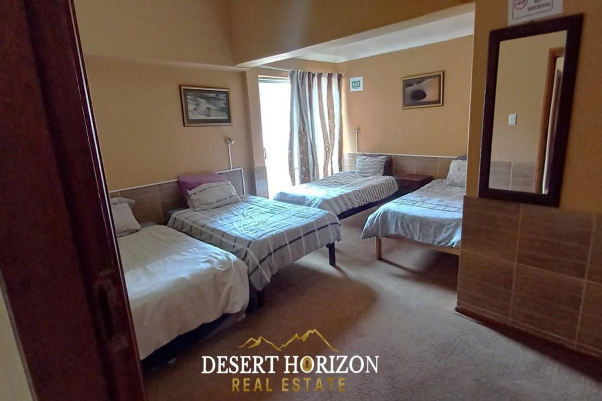 A spacious bedroom featuring neutral wall tones, tiled wall accents, and a sliding glass door providing access to the exterior.
