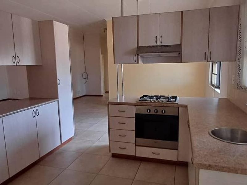 A functional kitchen featuring laminate cabinetry, built-in oven with gas hob, extractor fan, and stainless steel sink, offering a clean and practical layout.