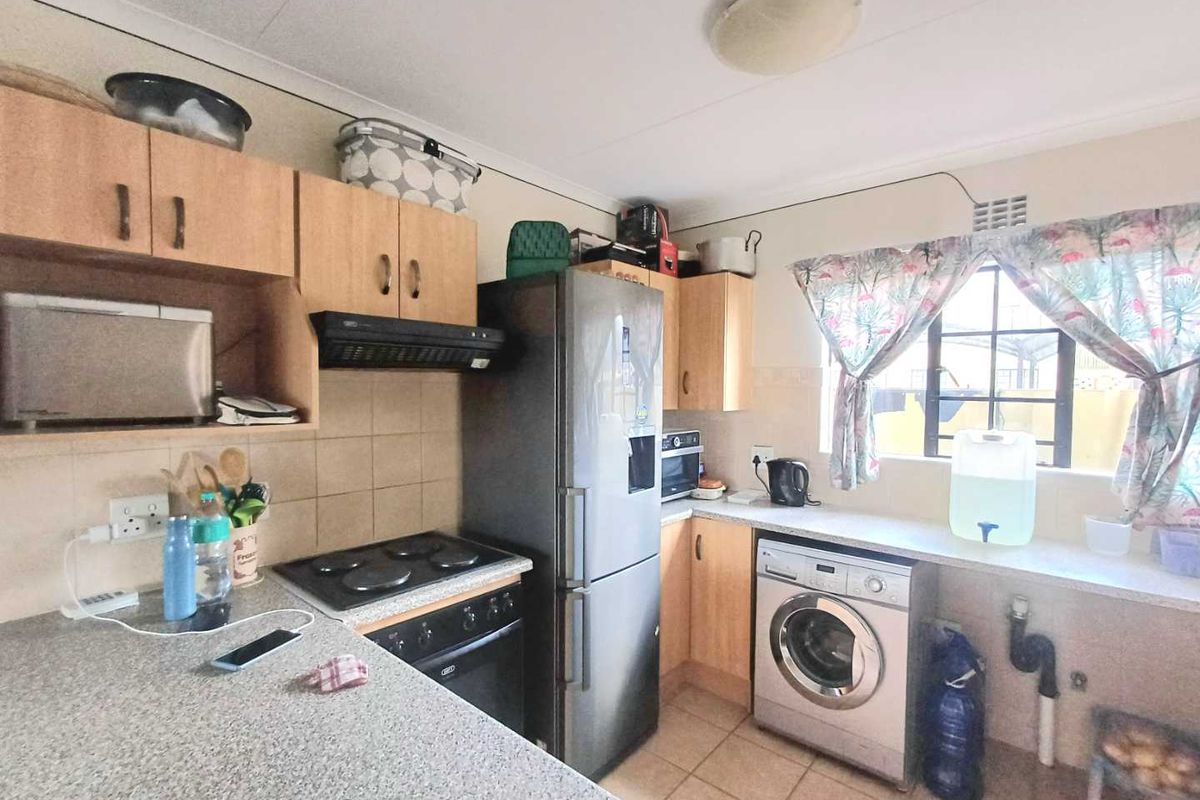 Functional kitchen featuring laminate countertops, built-in cabinetry, integrated stove with extractor fan, and dedicated space for a washing machine.