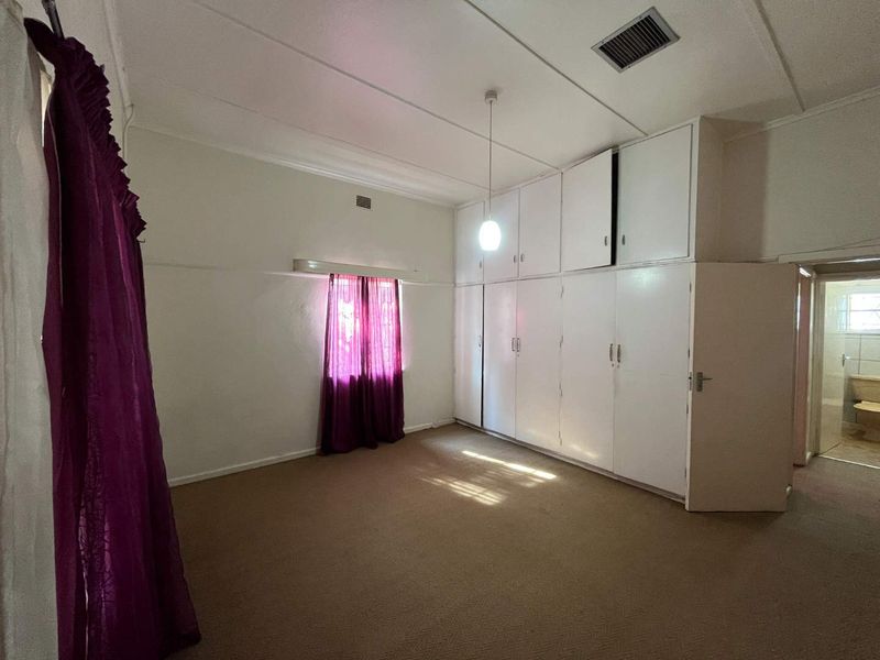A spacious bedroom featuring extensive built-in floor-to-ceiling cabinetry, neutral walls, and carpeted flooring, offering a blank canvas for renovation.