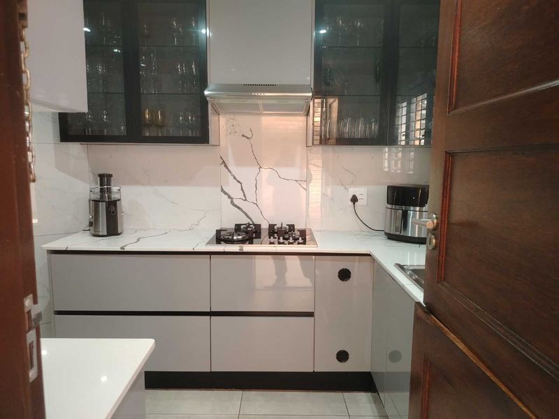 Modern kitchen featuring sleek grey cabinetry, marble-look splashback, gas hob with extractor fan, and high-quality quartz countertops.