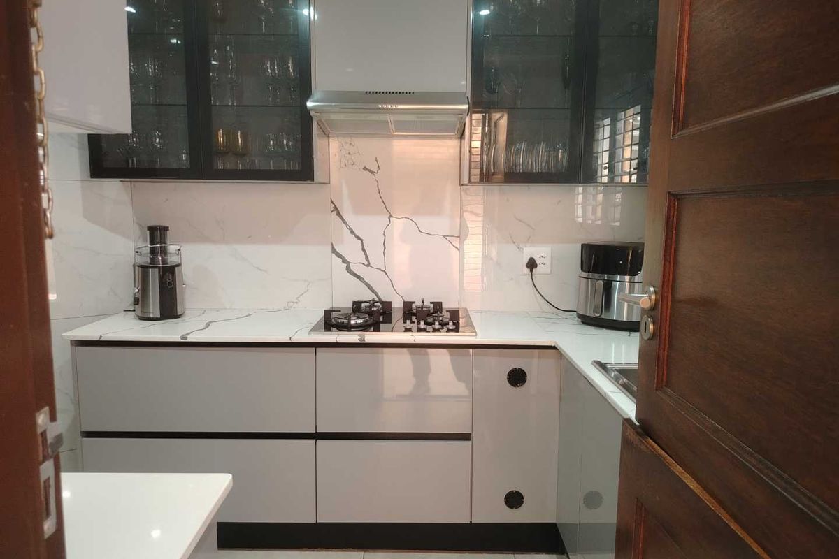 Modern kitchen featuring sleek grey cabinetry, marble-look splashback, gas hob with extractor fan, and high-quality quartz countertops.
