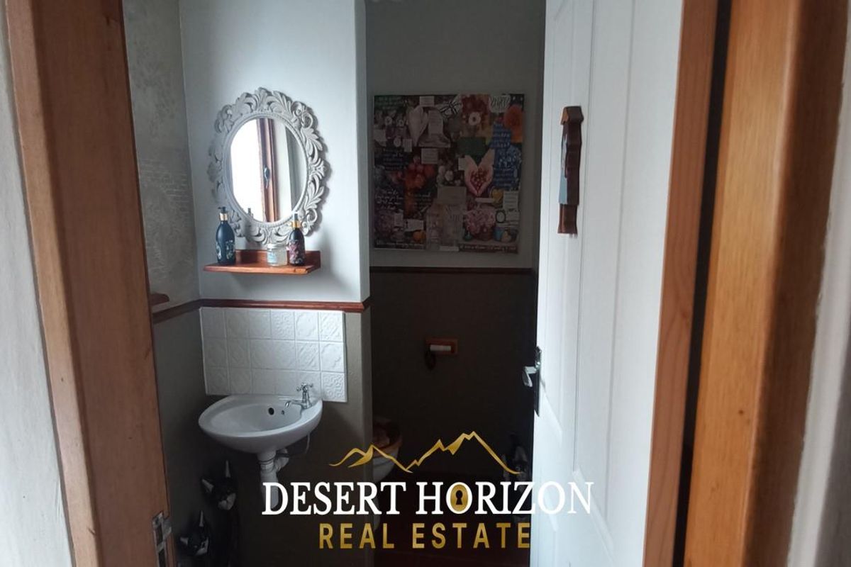A compact guest bathroom featuring a wall-mounted basin, tiled splashback, and decorative mirror.
