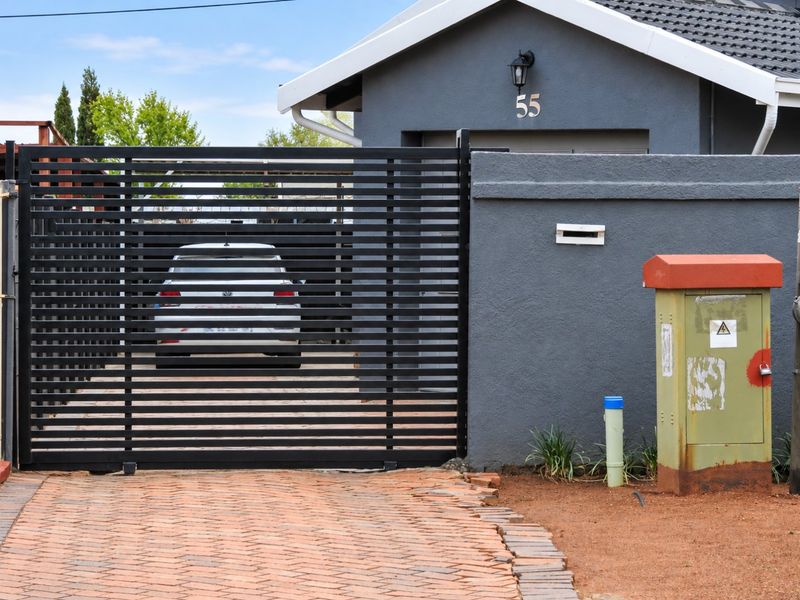 Front view of the property featuring a modern horizontal slat sliding gate, brick paved driveway, and a secure boundary wall.
