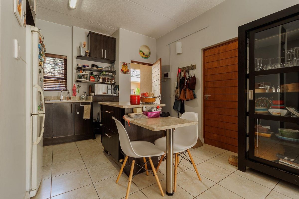 Compact kitchen featuring dark cabinetry, stone-look countertops, tiled flooring, and a central island with integrated breakfast bar seating.