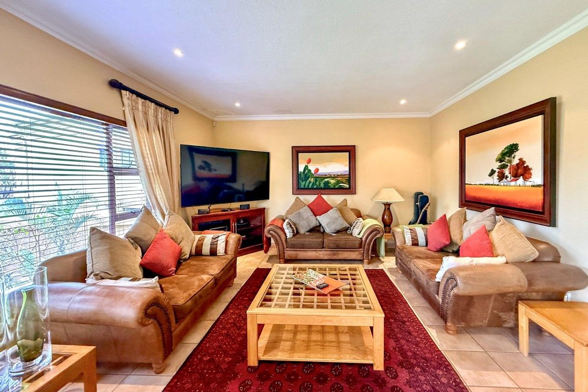 A comfortable living room featuring tiled flooring, recessed downlighting, and large windows with venetian blinds, creating a warm and inviting space.