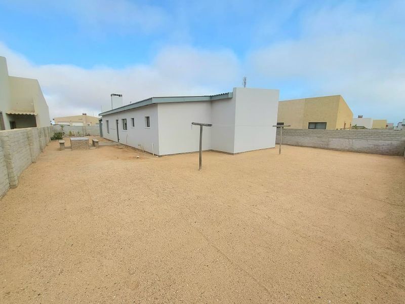 Spacious rear yard featuring a gravel surface, masonry boundary walls, and a clothesline, offering a blank canvas for landscaping and outdoor living improvements.