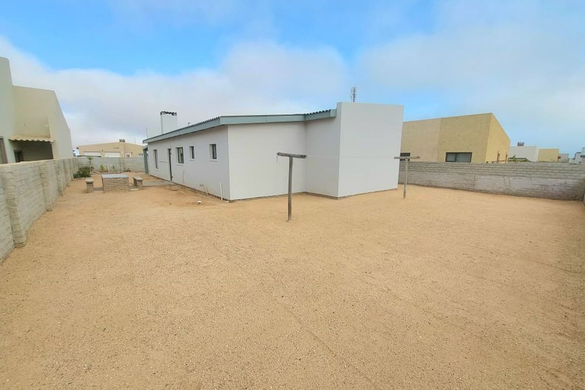 Spacious rear yard featuring a gravel surface, masonry boundary walls, and a clothesline, offering a blank canvas for landscaping and outdoor living improvements.