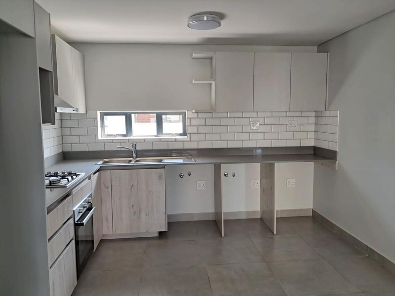 Modern kitchen featuring light wood-grain cabinetry, stone countertops, subway tile backsplash, and integrated appliances including a gas hob and oven.