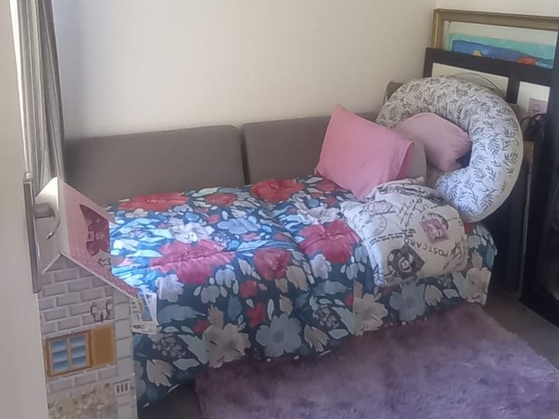 A compact bedroom featuring exposed ceiling beams and neutral wall finishes, suitable for a child's room or guest space.