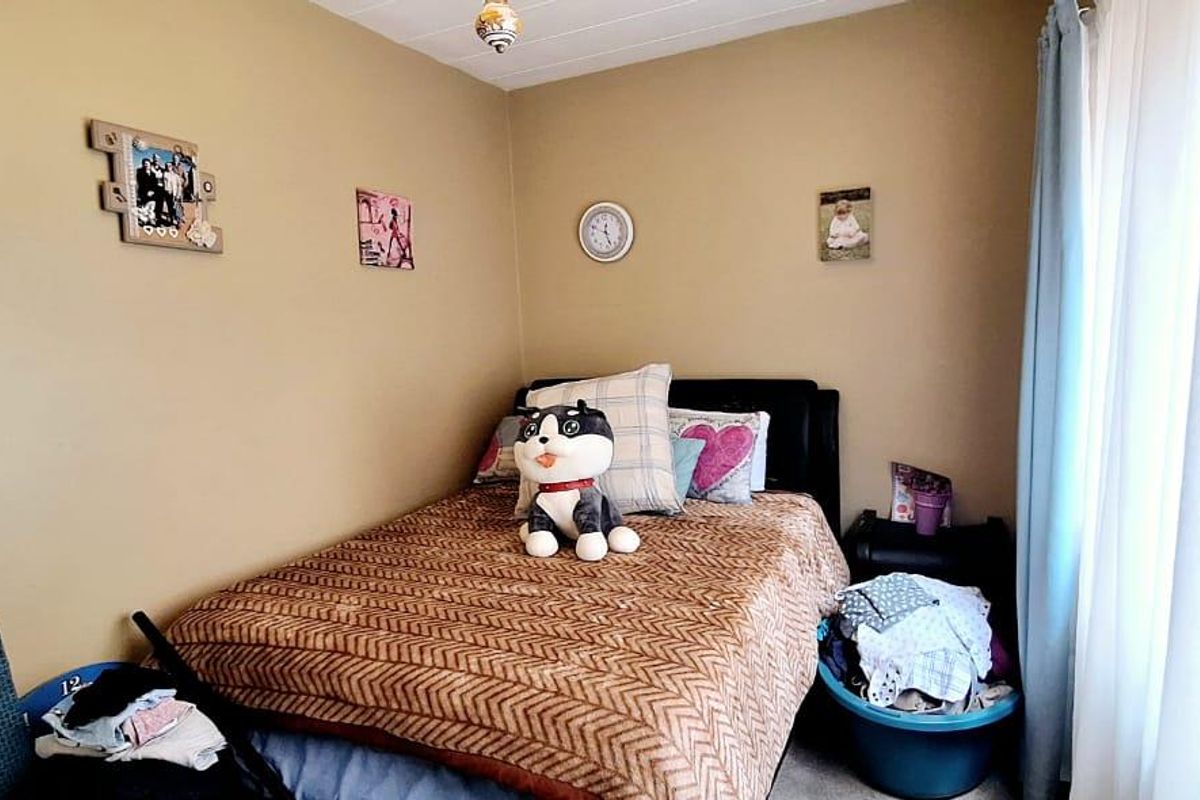 A compact bedroom featuring neutral wall tones, a window with curtain treatments, and a simple ceiling finish.