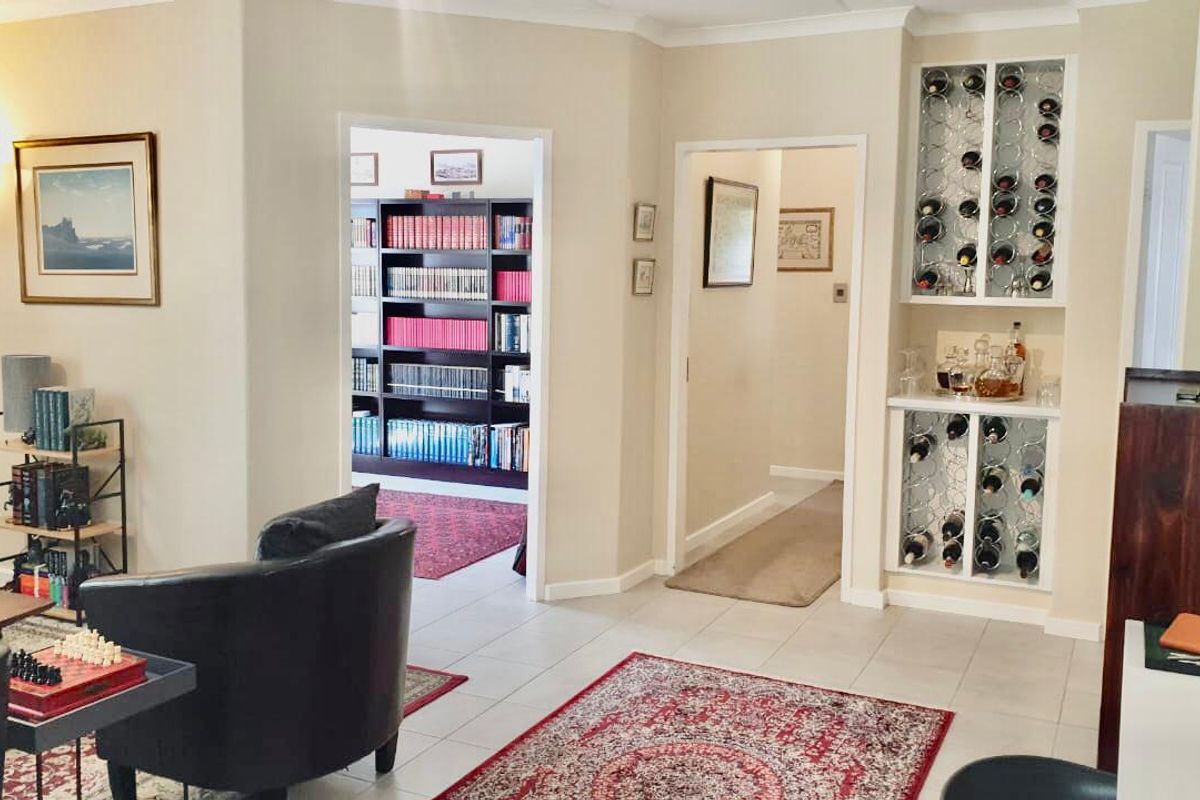 A well-maintained living area featuring a built-in wine rack and seamless flow into an adjacent library or study space.