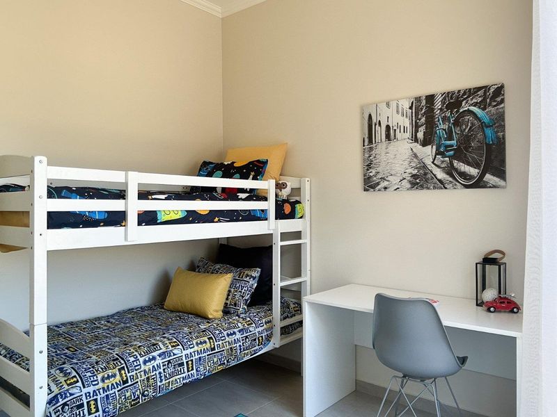 A well-maintained bedroom featuring neutral wall tones and durable tiled flooring, providing a clean and functional space.