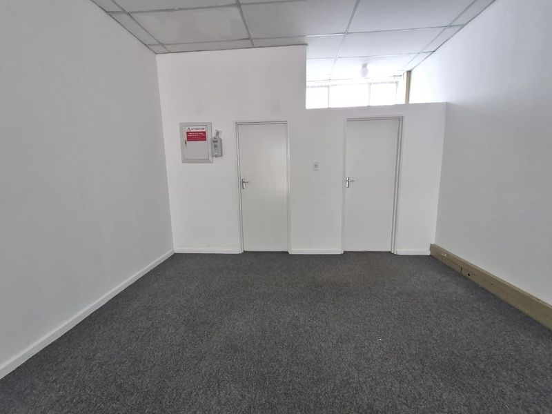 A vacant office space featuring grey carpeting, white walls, and a suspended ceiling, suitable for various retail or commercial business applications.