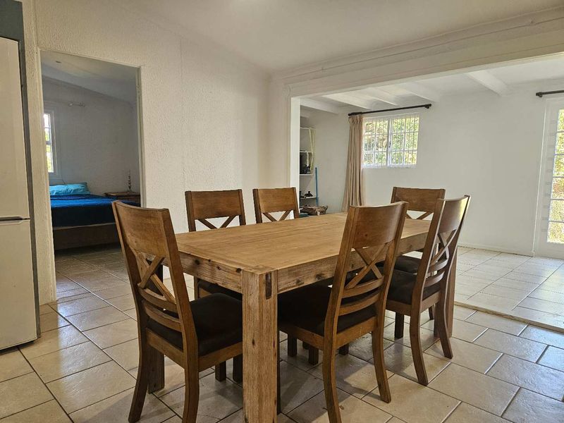 Open-plan dining area featuring tiled flooring, exposed ceiling beams, and natural light through multi-pane windows and french doors leading to the exterior.