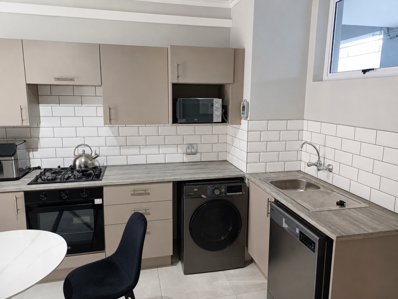 Modern kitchen featuring neutral cabinetry, subway tile backsplash, integrated appliances, gas hob, and a stainless steel sink with a mixer tap.