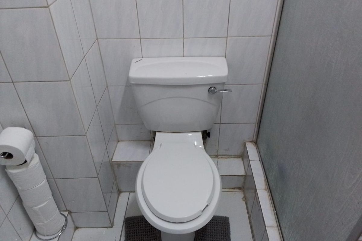 A functional bathroom space featuring a standard white ceramic toilet and tiled wall and floor finishes.