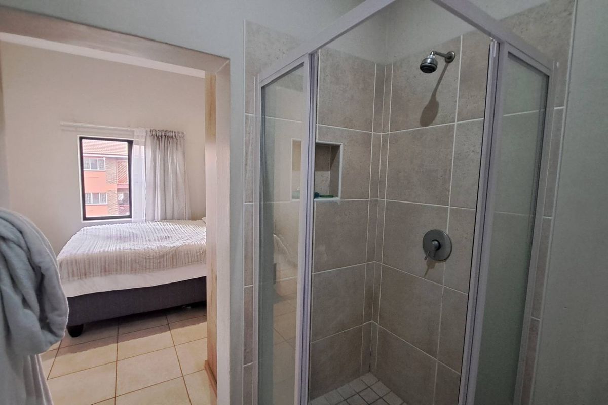 A functional bathroom featuring a tiled shower enclosure with a built-in niche, providing a clean and practical space.