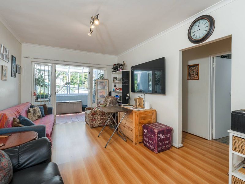 A living room featuring laminate flooring, coving, and a sliding glass door providing access to an outdoor patio area.
