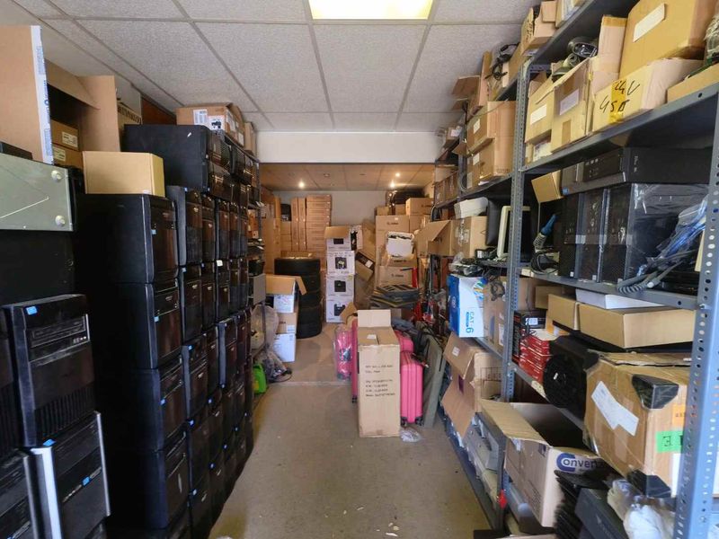 A cluttered utility or storage room featuring industrial metal shelving units and a suspended ceiling with recessed lighting.