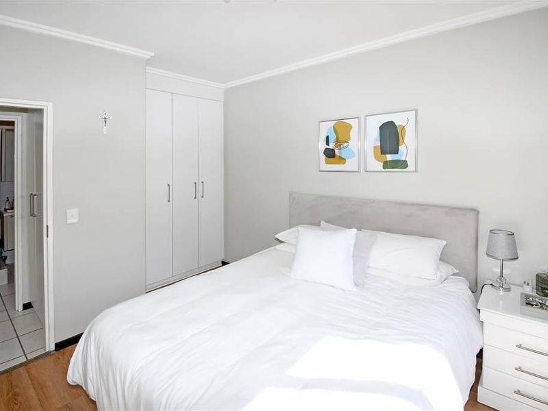 A well-maintained bedroom featuring laminate flooring, built-in cupboards, and direct access to an en-suite bathroom.