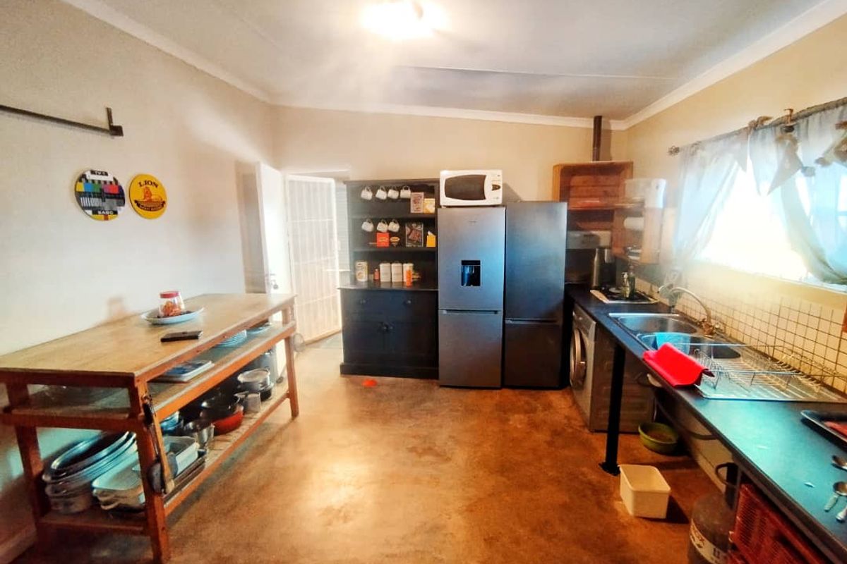 A functional kitchen area featuring concrete flooring, a double basin sink with tiled splashback, and built-in cabinetry for storage.