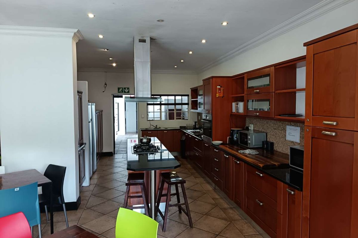 Spacious kitchen featuring dark wood cabinetry, granite countertops, a central island with a gas hob, and an integrated extractor fan.
