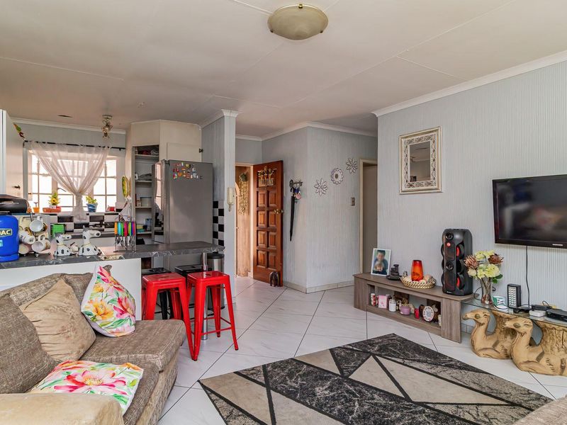 Open-plan living area featuring tiled flooring, a breakfast bar, and integrated kitchen cabinetry, creating a functional and connected living space.