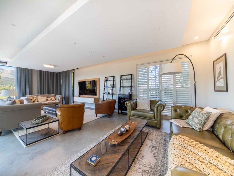 Spacious, modern living room featuring polished concrete floors, recessed ceiling lighting, ducted air conditioning, and large sliding doors leading to an outdoor area.