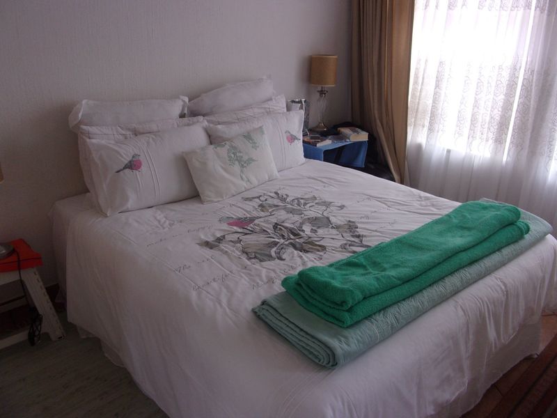 A standard bedroom featuring laminate flooring and window treatments, providing a functional and neutral space for rest.