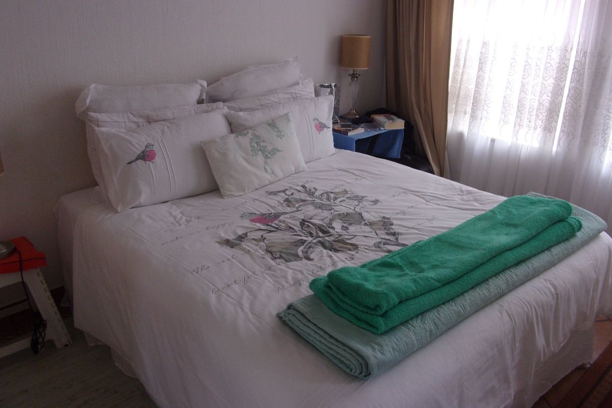 A standard bedroom featuring laminate flooring and window treatments, providing a functional and neutral space for rest.