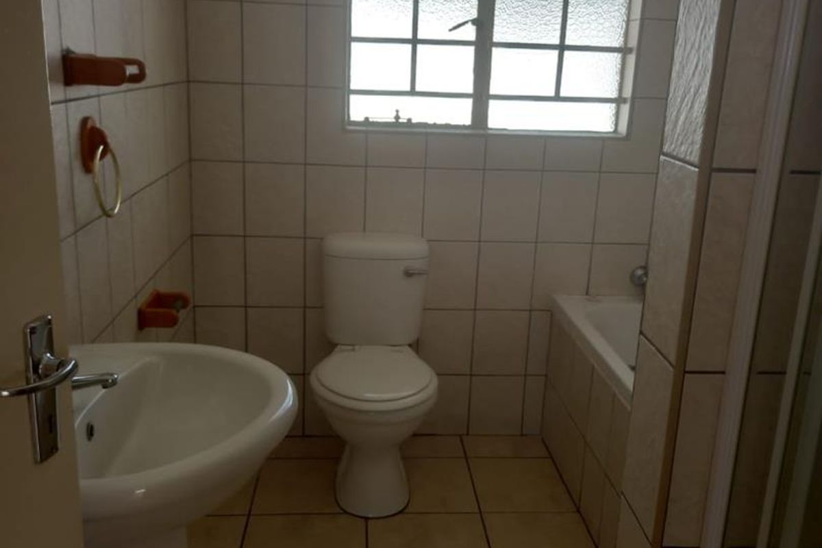 A functional bathroom featuring a pedestal basin, toilet, and a built-in bathtub with tiled walls and flooring.