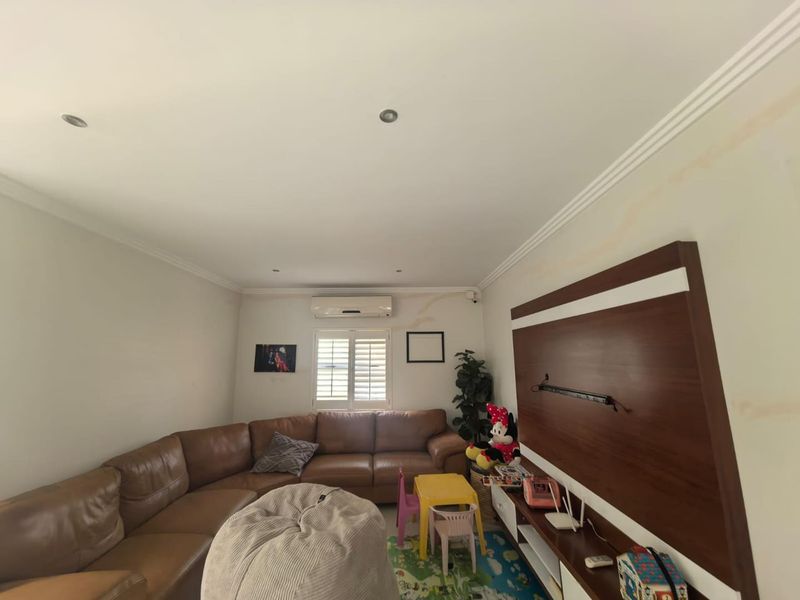 Living room featuring crown molding, recessed lighting, a split-system air conditioner, plantation shutters, and a built-in media wall unit.