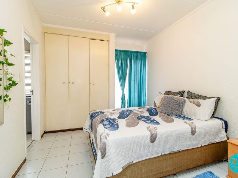 A functional bedroom featuring built-in cupboards, tiled flooring, and a ceiling light fixture, offering a clean and practical living space.