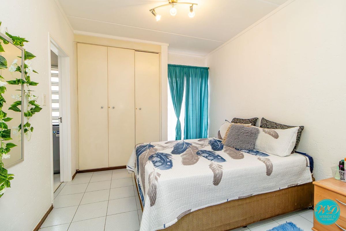A functional bedroom featuring built-in cupboards, tiled flooring, and a ceiling light fixture, offering a clean and practical living space.