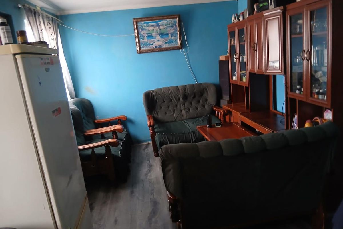 A living room area featuring laminate flooring and coved ceilings, currently used as a multi-purpose living space.