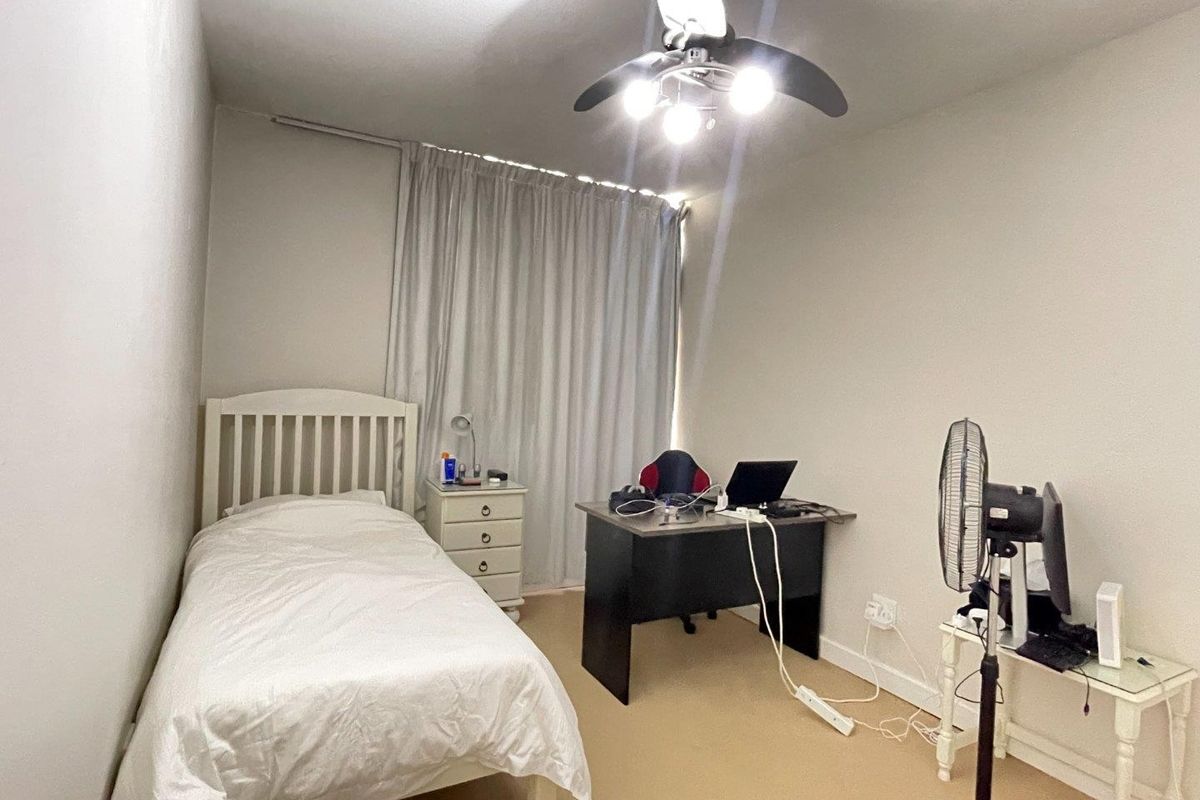 A functional bedroom featuring a ceiling fan, neutral carpeting, and window curtains, providing a comfortable space for rest or study.