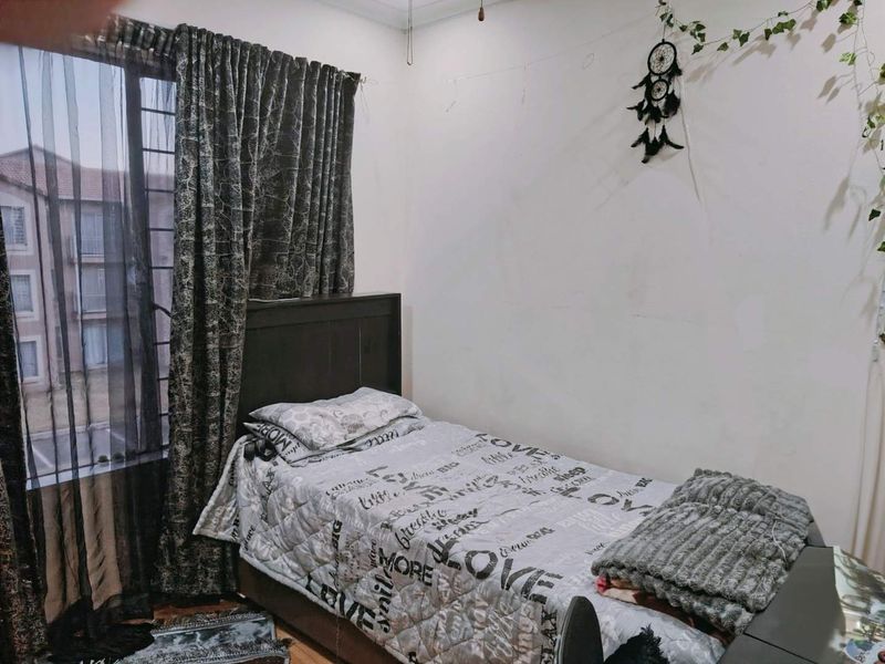 A standard bedroom featuring a window with security bars and neutral wall finishes, offering a functional space for rest.